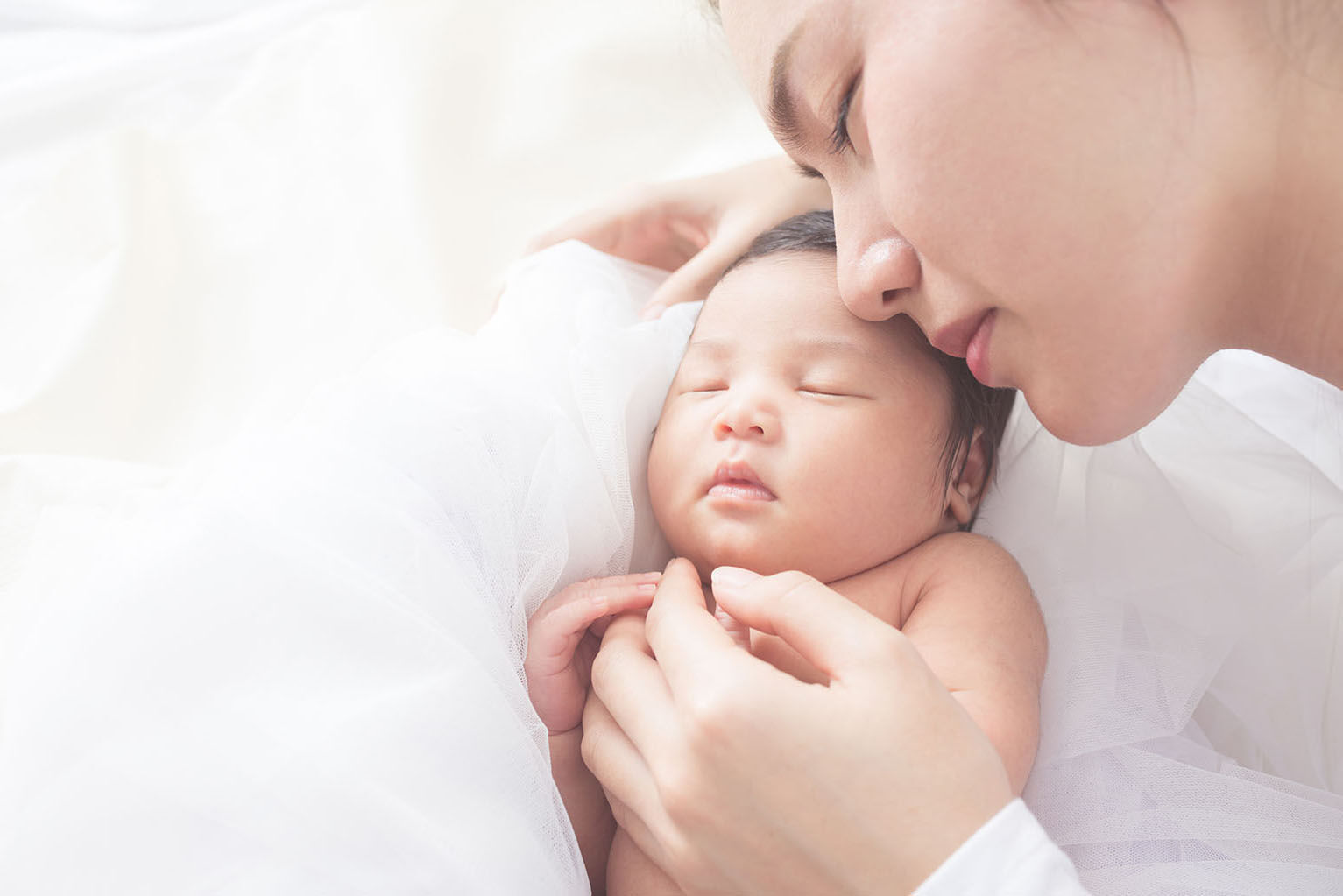 a mother snuggling with her sleeping baby
